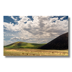 Sweeping views of green craters under a cloud-filled sky on the Babbit Ranch, showcasing the natural splendor just north of Flagstaff, Arizona.