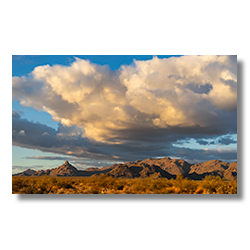 The last rays of sunlight illuminate the peaks around Date Creek, with clearing clouds adding drama to the Arizona sky.