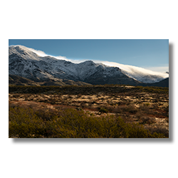 Snow blankets the rugged peaks of Yarnell, contrasting the warm desert terrain of Congress, Arizona.