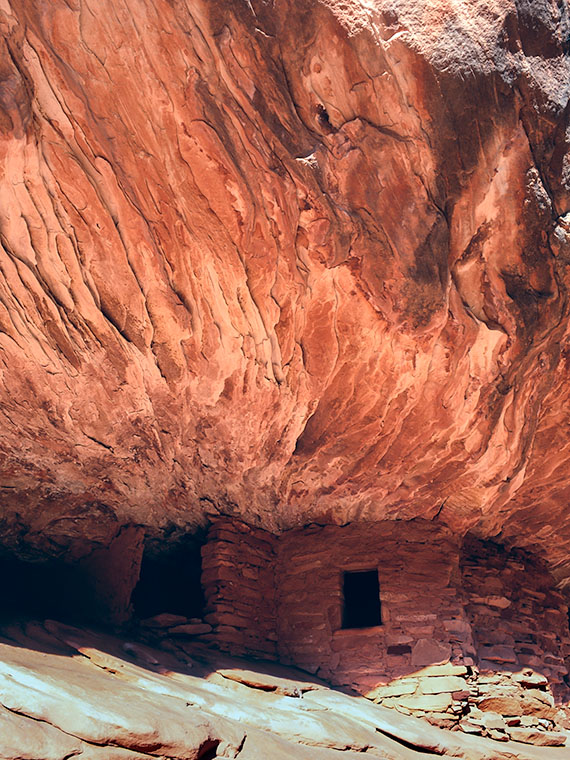 Anasazi-era ruin built into a sandstone wall with fiery patterns on Cedar Mesa, Utah.