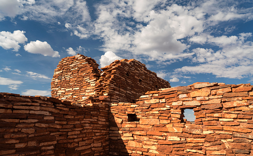 The Lomaki ruins at Wupatki National Monument, resembling cinder cone formations against a backdrop of dynamic clouds.