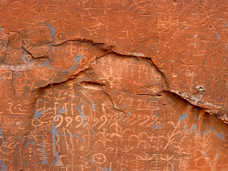 Confront the harsh reality of 'vandalizedGraffiti', where the sacred petroglyphs on Navajo land near Tuba City bear the marks of modern disregard on ancient canvases.