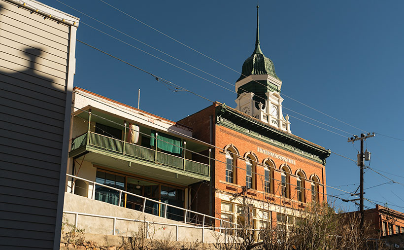 The green and white clock tower of the red brick Pythian Castle punches into the cold clear winter sky in Bisbee, Arizona.