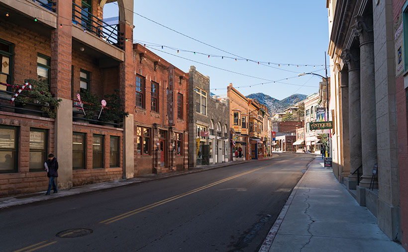 A view of Bisbee's Main Street, with its colorful storefronts, snow-capped mountains, and decorative lights