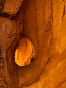 An erosion-formed window in a sandstone canyon wall, illuminated by sunlight at Gold Butte, photographed by Jim Witkowski.
