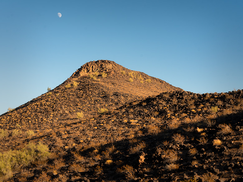 Basalt-covered mountain peak in Agua Caliente, likely formed by volcanic fissure eruptions, with the moon rising above.