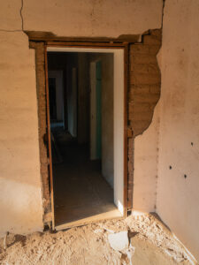 Back door of Palmerita Ranch house with falling plaster revealing adobe block walls.