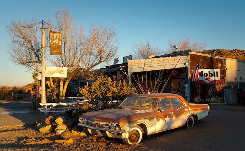 Rustic Hackberry General Store at sunrise with a weathered patrol car and classic gas station signs, capturing Route 66 nostalgia in Arizona.