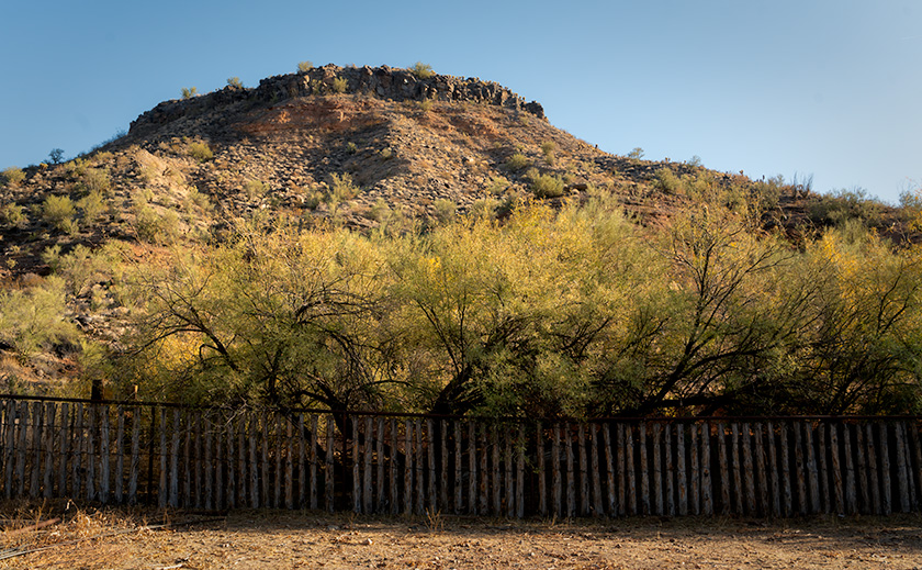 Rustic corral fence with desert bluff and trees at Palmerita Ranch in Arizona.