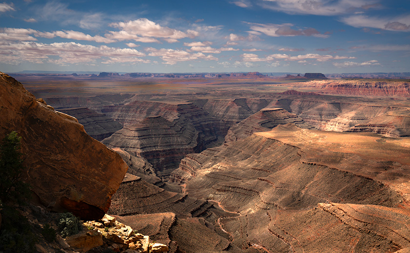 View from Muley Point of the San Juan River goosenecks with Monument Valley in the distance and cloud shadows on the ground