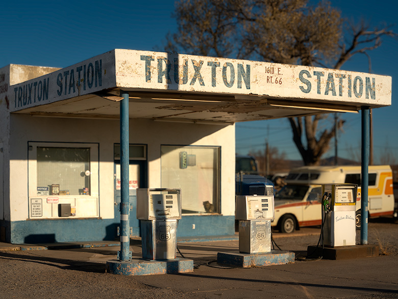 Vintage gas station with faded signage and classic Route 66 fuel pumps in Truxton, Arizona, bathed in morning sunlight.