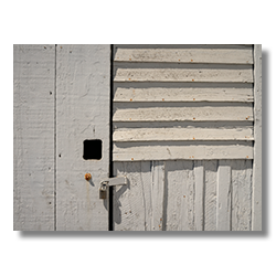 Close-up of a weathered door with a padlock, showing the rustic texture of a building at Pierce Point Ranch, Point Reyes, California