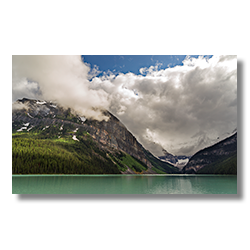The turquois waters of Lake Louise sparkle under a layer of clouds.