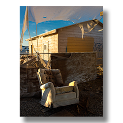 In the early morning, a rocker sits in the shade of a guaze curtain.