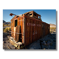 Weathered caboose car parked outside the historic Rhyolite hotel in Nevada.