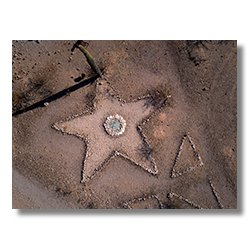 Drone photo of a five-point star made of stones with a blue-glass center, surrounded by desert terrain near Sundad, Arizona