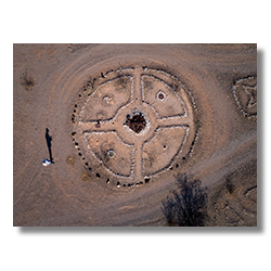 Drone photo of large rock circle in Sundad, Arizona with four quadrants, a rusted center, and the photographer’s shadow on the left