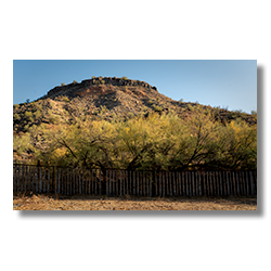 Rustic corral fence with desert bluff and trees at Palmerita Ranch in Arizona.