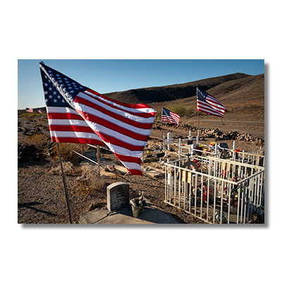 Agua Caliente Pioneer Cemetery with American flags flying over graves on Veterans Day, restored with white crosses.