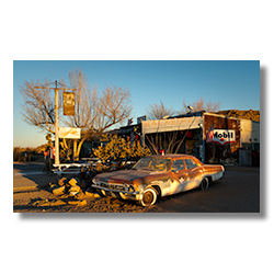 Rustic Hackberry General Store at sunrise with a weathered patrol car and classic gas station signs, capturing Route 66 nostalgia in Arizona.