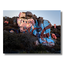 Overview of Roy Purcell’s murals in Chloride, Arizona, showcasing a central cosmic-themed mural surrounded by smaller painted rocks in the Cerbat foothills.