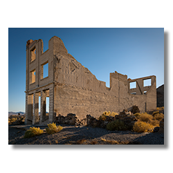 Ruins of the historic Cook Bank building in Rhyolite, Nevada illuminated by the last rays of sunlight.