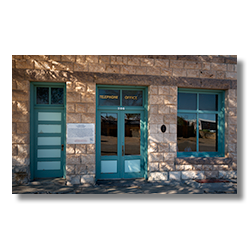 Facade of Goldfield, Nevada’s historic telephone company with aqua windows and door in bright dappled sunlight