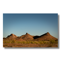 Three desert peaks surrounded by cacti and brush, photographed in Arizona near Signal Mountain Wilderness.