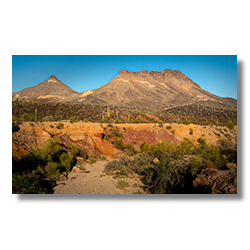 Cooper Wash cutting through red rock layers with Montezuma Head and Face Mountain ridges in the Arizona desert.