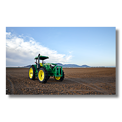 A big John Deer tractor sits in an empty cotton field in Aguila Arizona.